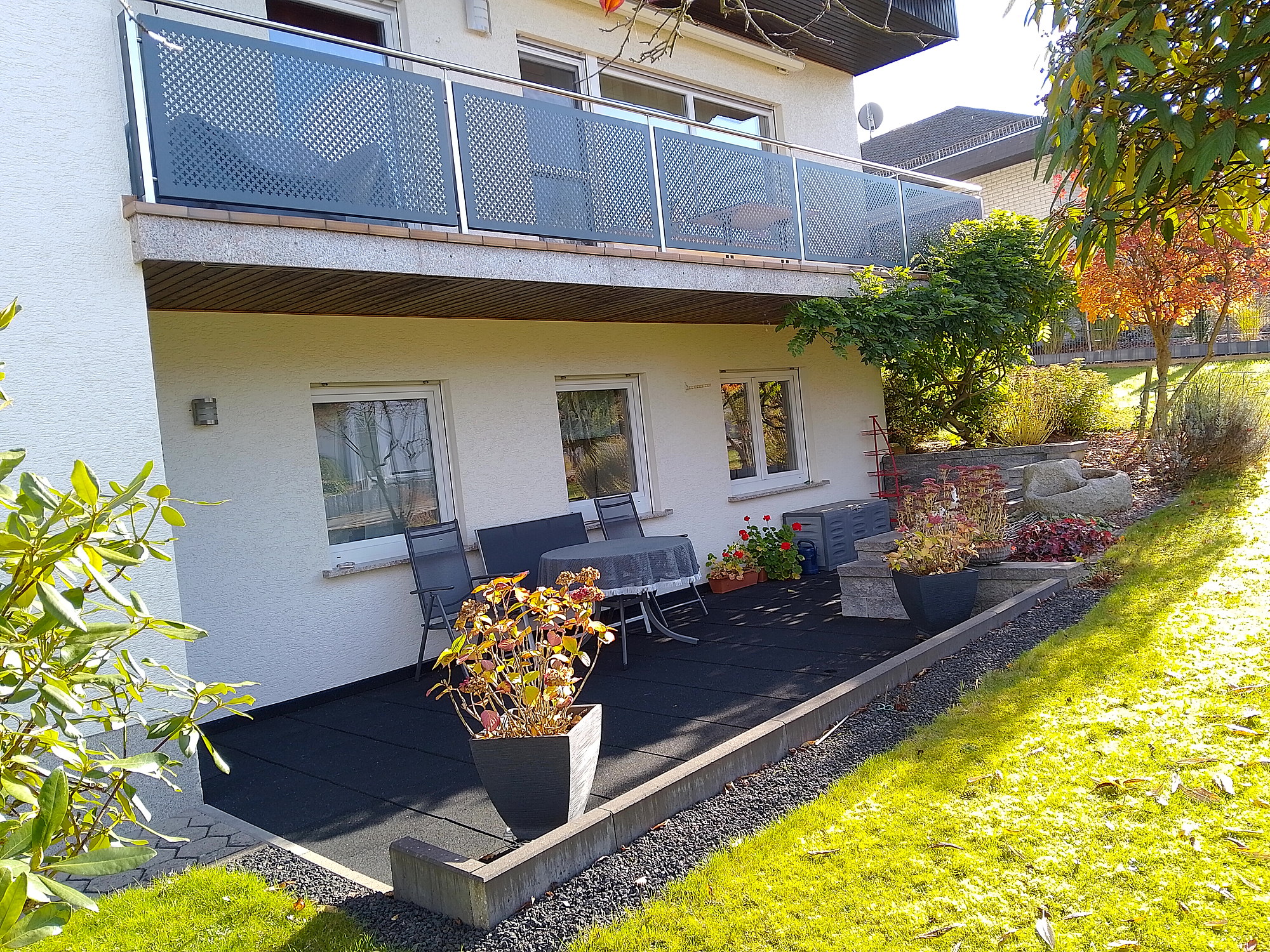 Geschützte Terrasse der Ferienwohnung mit Sitzgruppe und Blick ins Grüne