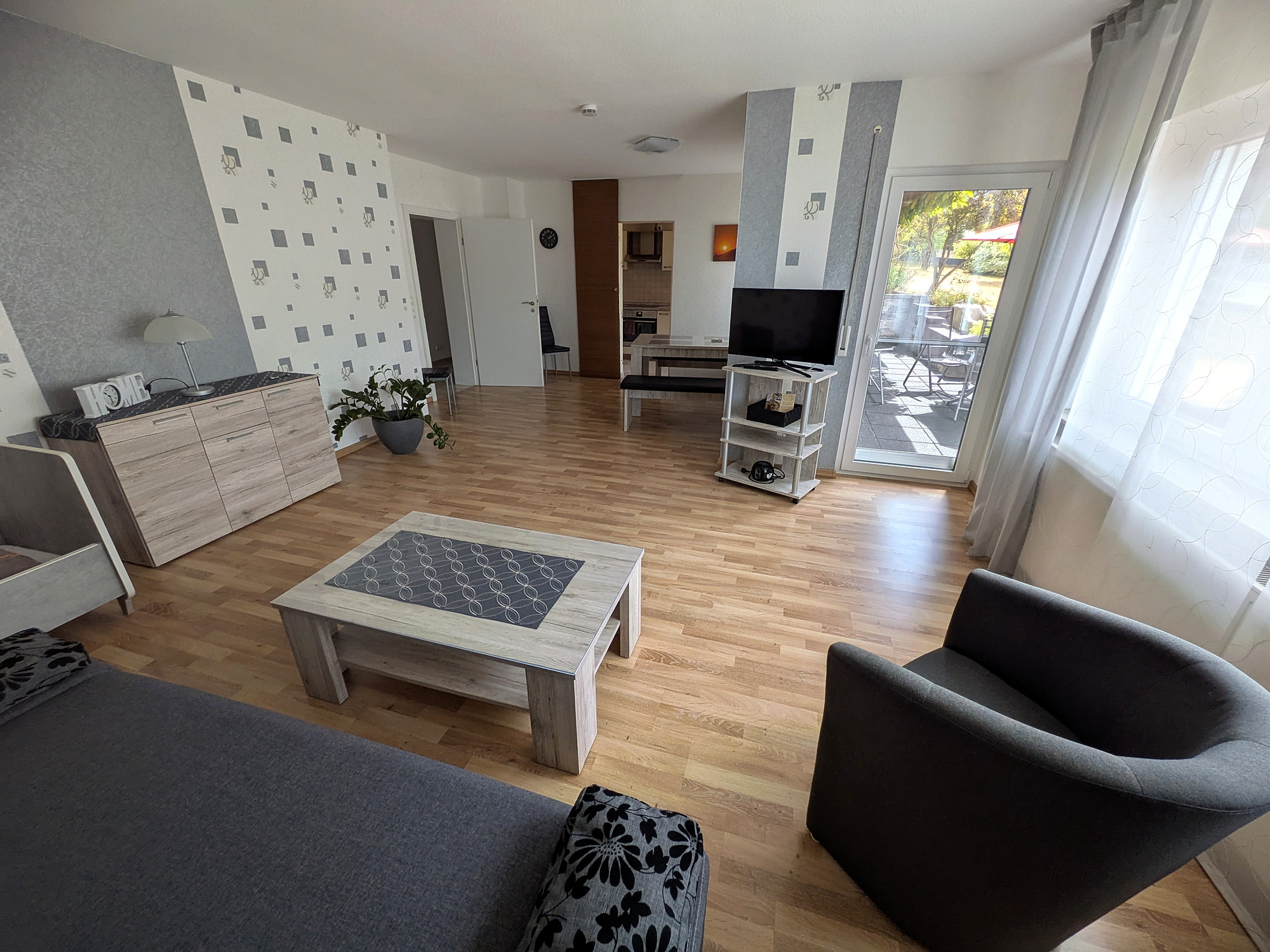 Heller Wohnbereich mit Sitzecke, Essplatz und Zugang zur Terrasse