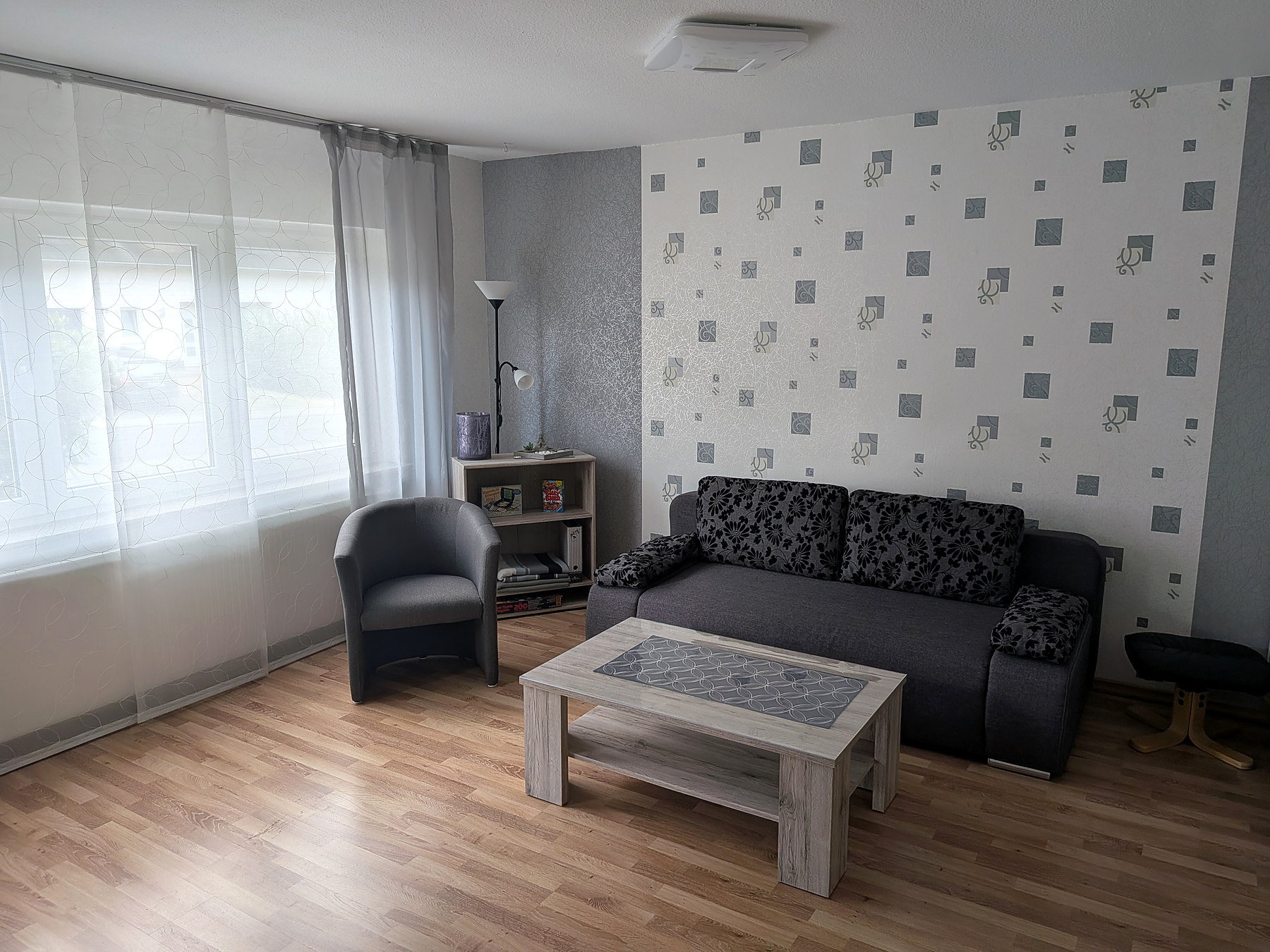 Wohnraum mit Schlafsofa, Sessel, Couchtisch und SAT-TV